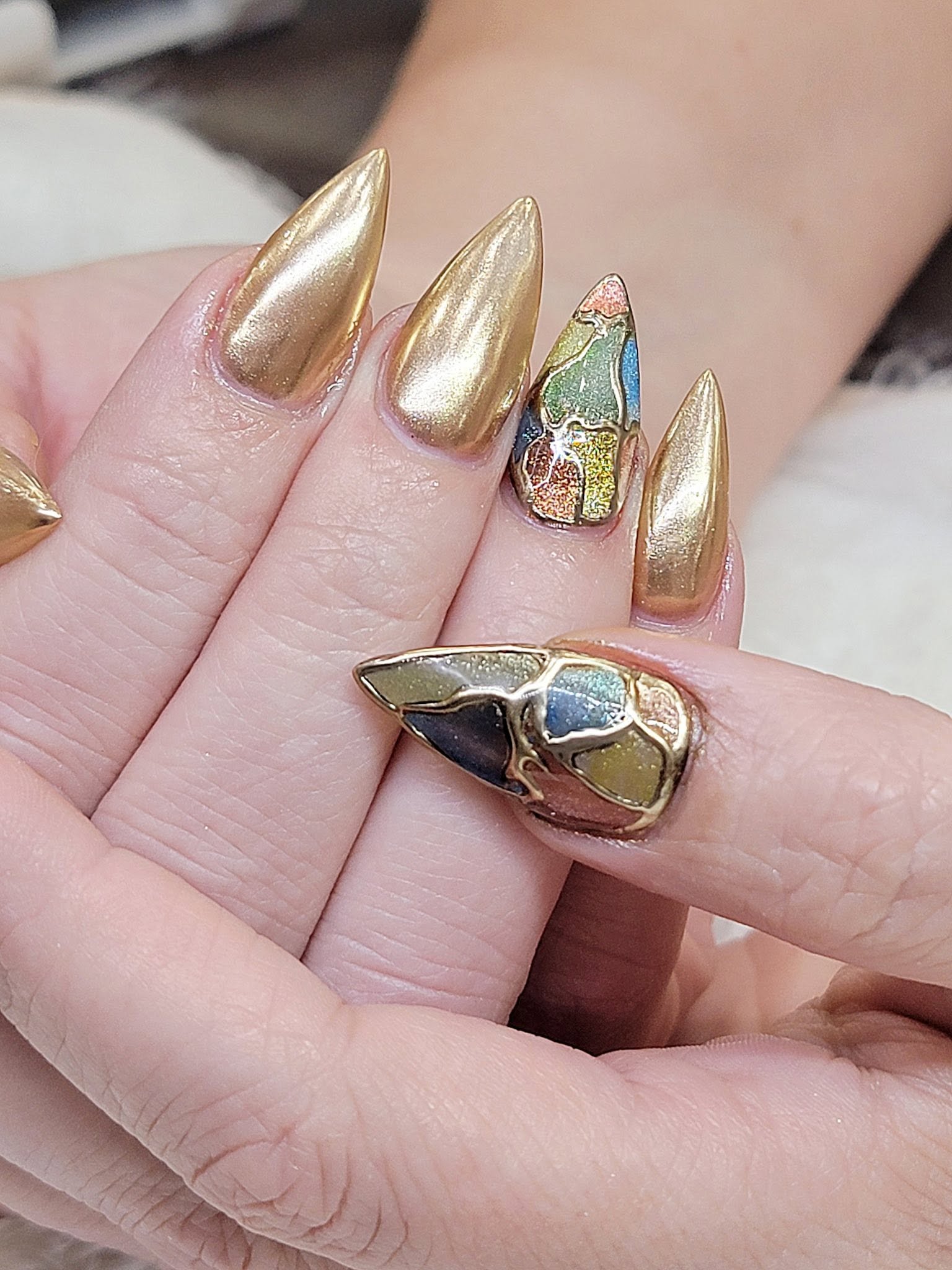 Bold gold chrome stiletto nails with a hand-crafted mosaic accent nail by LaVie Nails